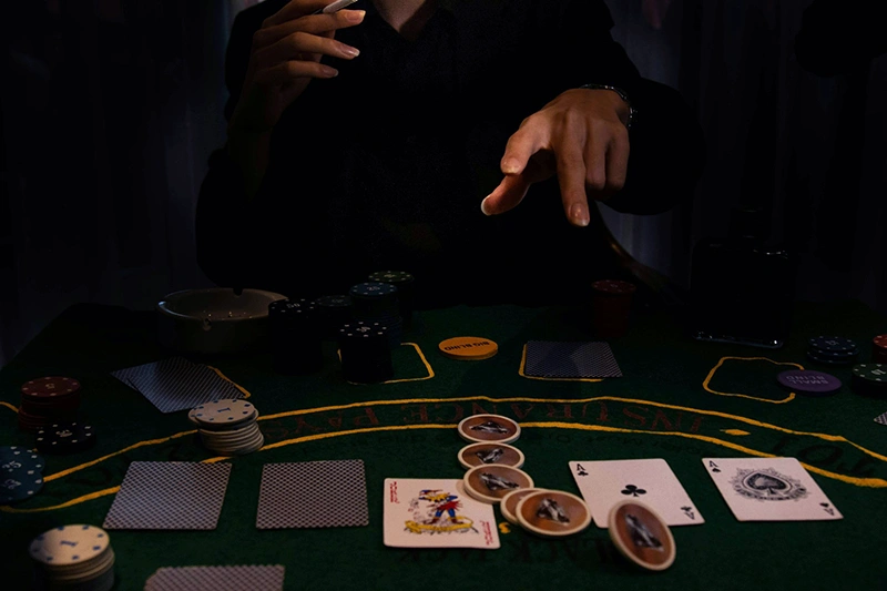Main d'un joueur distribuant des cartes et des jetons sur une table de poker